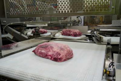 Cryovac machine with beef on conveyor