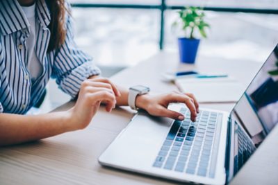 Cropped image of female hands searching web information during social networking via modern laptop computer, woman connecting to wifi wireless for making online netbook booking and banking