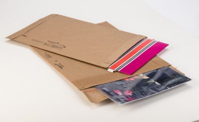 a pink and orange striped folder and a magazine, each packaged in a Jiffy utility mailer