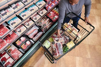 man placing tray of meat in grocery cart