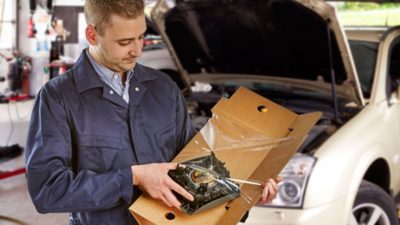 mechanic in garage removing an auto part from package