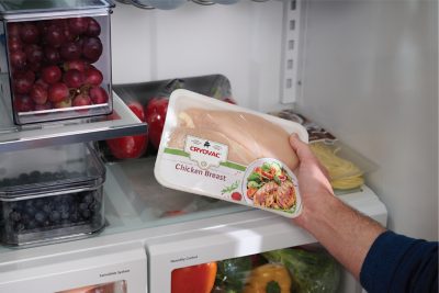 CRYOVAC® Compostable Overwrap Tray being placed into a kitchen refrigerator