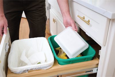 CRYOVAC® Compostable Overwrap Tray being placed into a kitchen compost bin