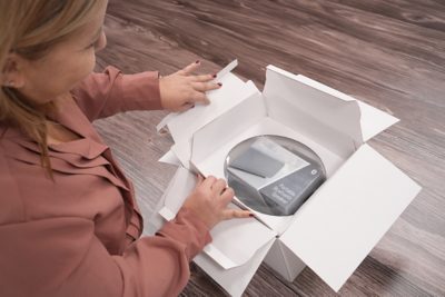 woman opening a white box containing a portable bluetooth speaker