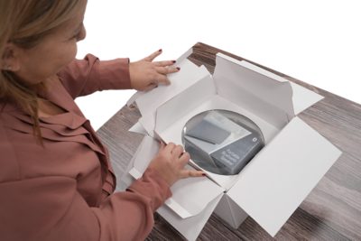 woman opening a white box containing a portable bluetooth speaker